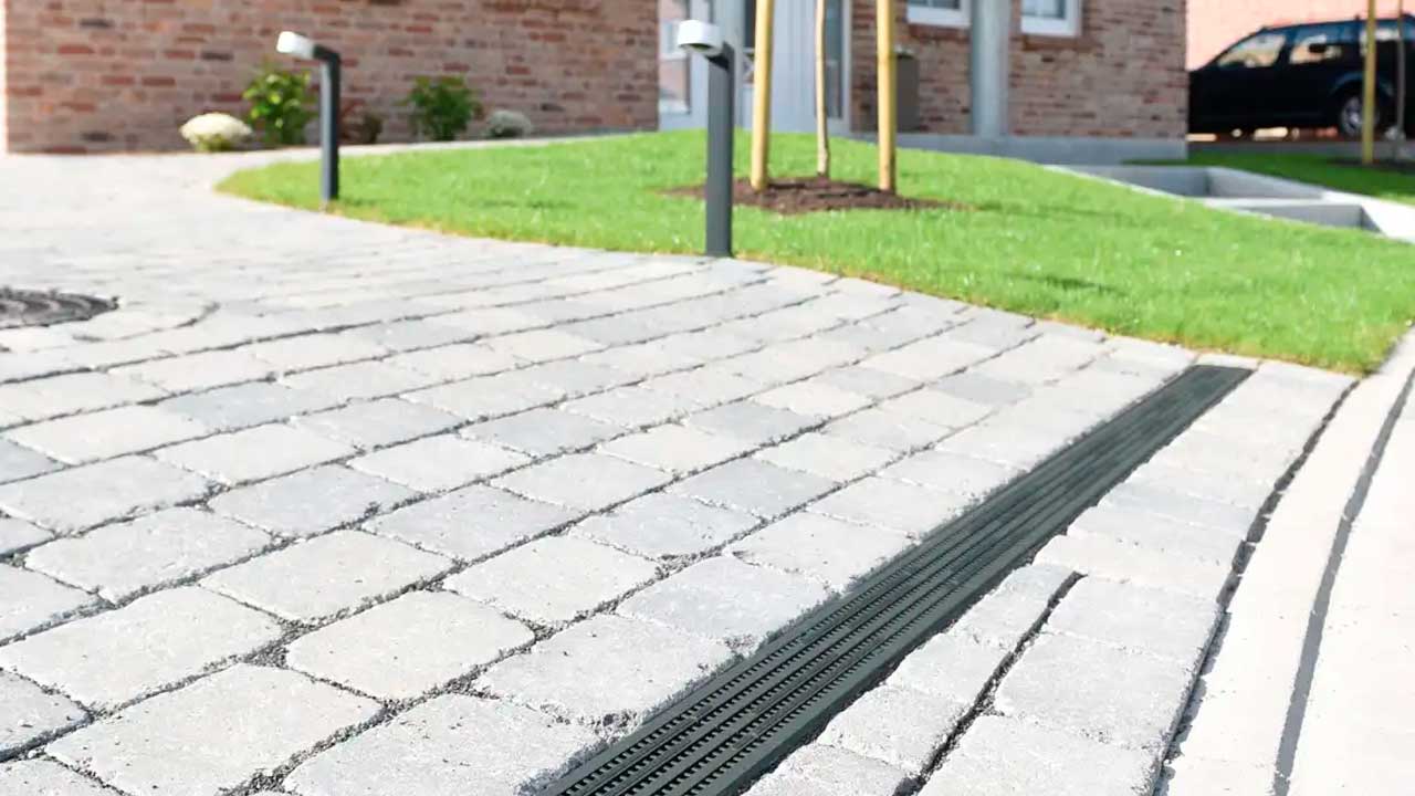 Smalt linjedræn i indkørsel med belægningssten